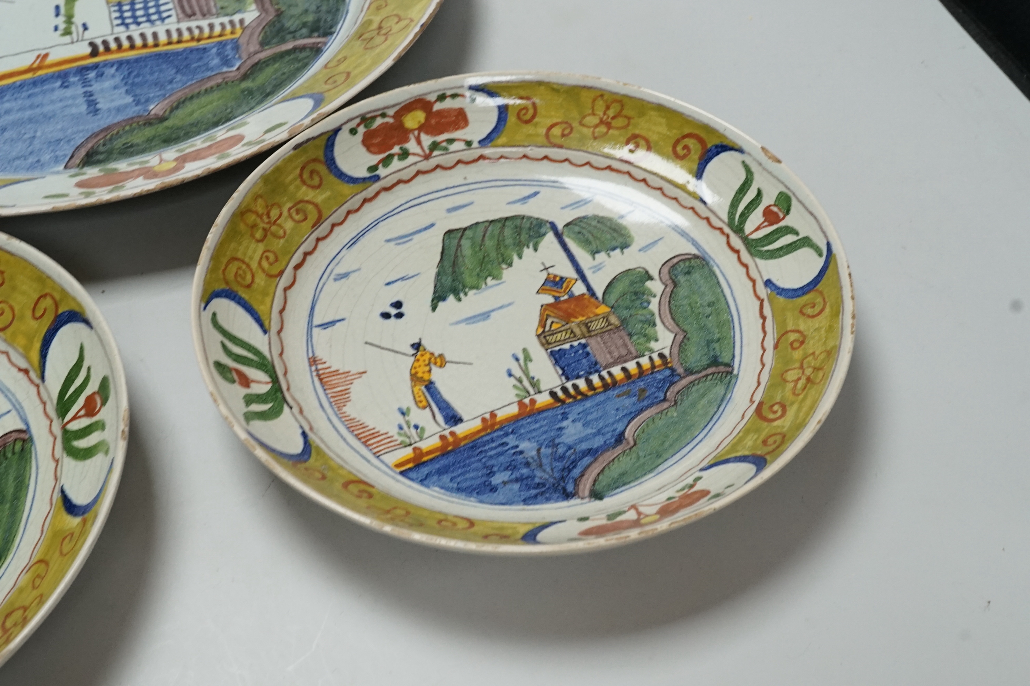 A Delft charger and a pair of similar dishes, largest 34cm diameter